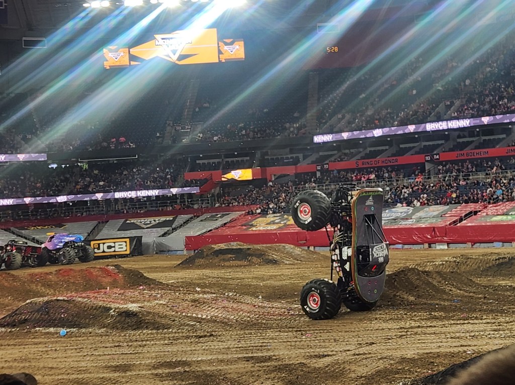Wreck-Deck Tech-Deck, a popular Monster Truck, performing a front balance while other Monster Trucks and a large audience watch in awe.